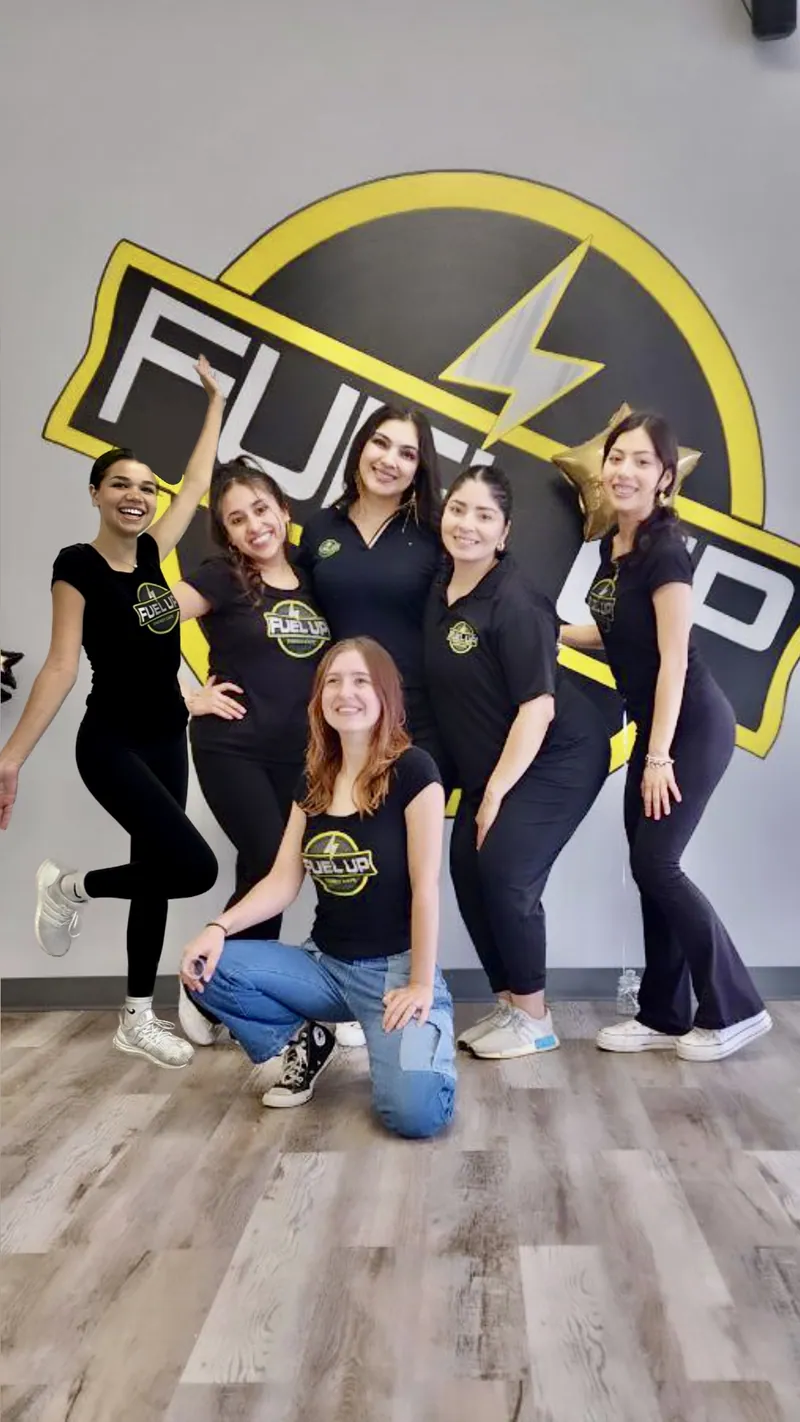 The Fuel Up team posing in front of the Fuel Up logo wall