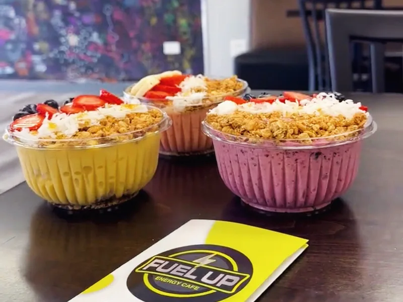 Three superfood bowls topped with granola, coconut and fresh fruit on a table inside Fuel Up Energy Cafe in Bolingbrook, IL